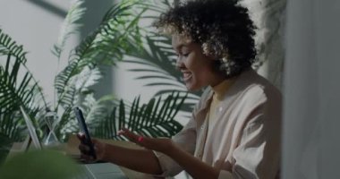 Genç bayan serbest çalışan internet üzerinden konuşuyor ve ev telefonuyla el sallıyor. İnternet iletişimi ve serbest çalışma kavramı.