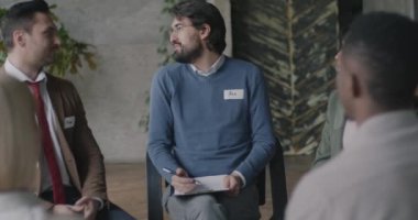 Neşeli gençler grup halinde oturup iş yerinde takım oluşturma etkinliğinin tadını çıkarıyorlar. Psikoloji ve terapi seansı konsepti.