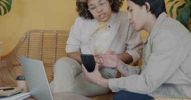 İki iş adamı Asyalı ve Afrikalı Amerikalı akıllı telefon ekranına bakarak ofiste yeni fikirlerin tartışılmasını konuşuyor. İş ve iletişim konsepti.