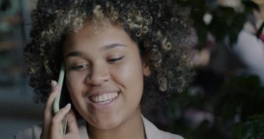 Genç Afro-Amerikalı bir kadının cep telefonuyla gülüşü iş konuşmalarına yoğunlaşmıştı. Cep telefonu iletişimi ve insan kavramı.