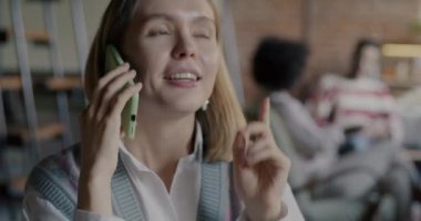 Neşeli genç bayan cep telefonuyla konuşuyor. Kreatif kafede serbest çalışma projesini tartışıyorlar. İş ve profesyonel iletişim kavramı.