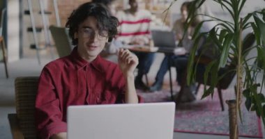 Modern açık uzay ofisinde işi tartışan yaratıcı girişimci dizüstü bilgisayar ve kulaklıkla çevrimiçi video görüşmesi yapıyor. Eş zamanlı ve sanal buluşma kavramı.
