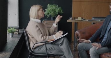 Orta Doğulu bir adam modern ofiste kadın terapistle iş sorunları hakkında konuşuyor. Profesyonel terapi ve psikoloji konsepti.