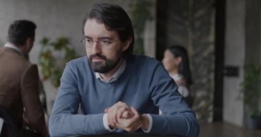 Grup terapisinde kameraya ciddi bir yüzle bakan Orta Doğulu genç bir adamın portresi. Psikoloji ve iyileşme kavramı.