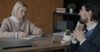 Psikolog, erkek müşterinin masada oturup yazılarını dinlerken erkek müşterinin klinikte sorunlarını paylaşmasını dinliyor. Psikolojik destek ve profesyonel psikanalist konsepti.