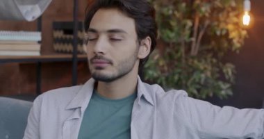 Orta Doğulu neşeli bir adamın yavaş çekim portresi kameraya çekiliyor ve akşam evde gülümsüyor. İnsanlar ve olumlu duygu kavramı.