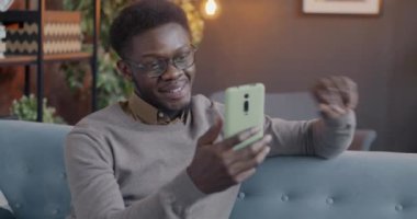 Neşeli bir Afrikalı Amerikalı, akşam evden çevrimiçi video görüşmeleri sırasında el sallıyor ve konuşuyor. İnsanlar ve iletişim konsepti.