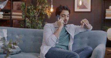 Kaygısız bir Arap, cep telefonuyla konuşuyor akşamları evdeki koltukta oturuyor. Gündelik iletişim ve cep telefonu teknolojisi kavramı.