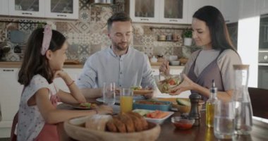 Şefkatli eş kocalarına salata hazırlıyor. Kızıyla birlikte evde yemeğin tadını çıkarıyor. Aile ilişkisi ve sağlıklı yaşam tarzı kavramı.