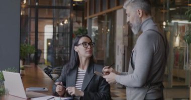 Neşeli genç iş kadını kafede sipariş veren olgun bir garsonla konuşuyor. Öğle yemeği molası ve iş adamları dışarıda yemek kavramı..