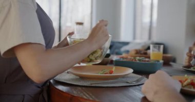 Kadın eli, mutfakta öğle yemeği yerken sebze salatasını tabağa koyuyor. Sağlıklı gıda ve beslenme konsepti.