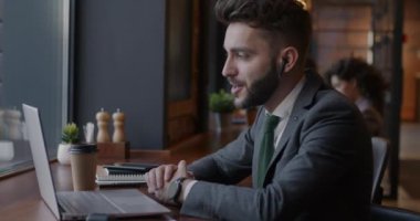 Bir yandan iş adamının internetten bilgisayar ve kafedeki kablosuz kulaklıkları kullanarak yaptığı görüntüler. İletişim ve modern teknoloji kavramı.