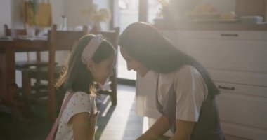 Sevgi dolu anne ve tatlı kız. Sevgiyi ifade ediyorlar. Güneşli mutfakta yerde oturuyorlar. Aile ilişkisi ve mutlu annelik kavramı..