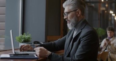 İşadamı, elinde kredi kartı bulunan dizüstü bilgisayarla Kafe 'deki masada ticaret ve bankacılık üzerine çalışıyor. Modern teknoloji ve ticari kâr kavramı.