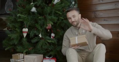 Mutlu aile konuşmalarının portresi ve Noel ağacının altında el sallayarak kameraya bakarak çevrimiçi video görüşmesi yapmak. Tatil ve iletişim konsepti.