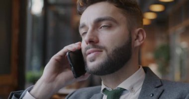 Cep telefonuyla konuşan genç iş adamının yakın plan portresi kafede iş tartışması. Cep telefonu iletişimi ve girişimci konsepti.