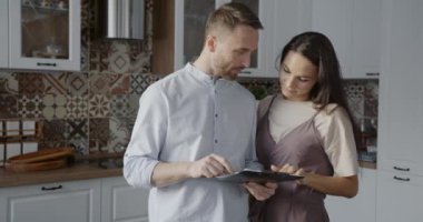 Karı koca kağıt okuyorlar. Evdeki mutfakta duran bilgileri tartışıyorlar. Aile yaşam tarzı ve iş anlaşması kavramı.