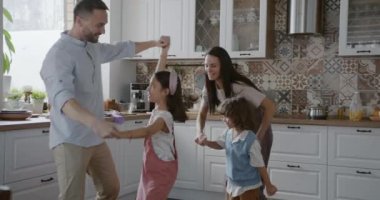 Neşeli insanların ağır çekimleri. Anne, baba ve çocuklar dans ediyor, zıplıyorlar, gülüyorlar, mutfakta eğleniyorlar. Aile ve modern yaşam tarzı kavramı.