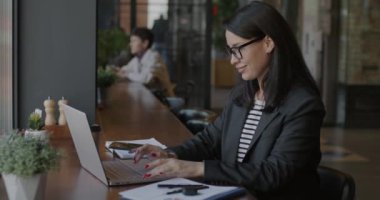 Laptop kullanan ve kafede profesyonel başarıların tadını çıkaran aşırı neşeli genç iş kadını. Pozitif duygu ve iş geliştirme kavramı.