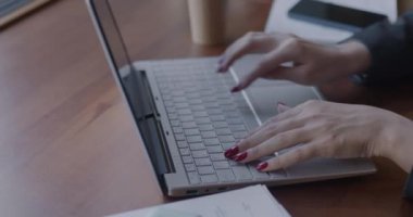 Bilgisayarla yazı yazan iş kadınının yavaş çekimde yakın çekimde görüntüsü. Sonra da kafede çalışan cep telefonuyla konuşuyor. İş ve iletişim kavramı.