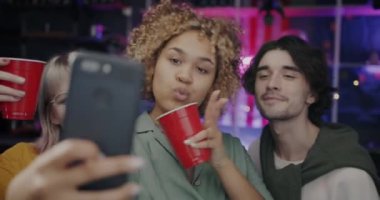 Akıllı telefon kamerası için poz veren bir grup genç arkadaş gece partisinde eğlenirken selfie çekiyorlar. Gençlik ve fotoğraf konsepti.