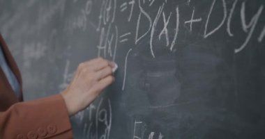 Öğretmen sınıfta matematik teorisini açıklarken, kadın el yazısı denkleminin yakın çekim yavaş çekimi. Eğitim ve bilgi kavramı.