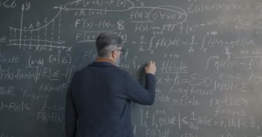 Araştırma enstitüsündeki matematik bilimi gelişimi ile ilgili yazı tahtasına semboller yazan erkek bilim adamının geçmişe bakış. İnsanlar ve keşif kavramı.