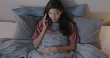 Kaygısız Asyalı kadının cep telefonuyla konuşması ve geceleri karanlık bir odada dinlenmesi. İletişim ve gençlik kavramı.