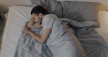 Pijamalı Afro-Amerikan bir adamın yatakta hareketli yatak odasında dinlenmesinin en güzel görüntüsü. Uyku ve uyku konsepti.
