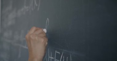 Kadın el yazısı formülünü karatahtaya yakın çekimde kadın öğrenci lisede öğrenirken. Eğitim ve bilim konsepti.