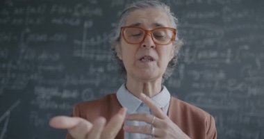 Online konferans sırasında konuşan kıdemli bayan bilim adamının portresi laboratuvarda kara tahtayla teoriyi açıklayan video konuşması yapıyor. Bilim ve iletişim konsepti.