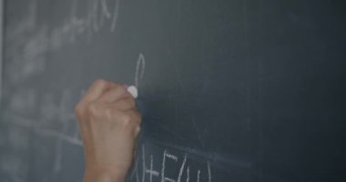 Kadın el yazısı formülünü karatahtaya yakın çekimde kadın öğrenci lisede öğrenirken. Eğitim ve bilim konsepti.