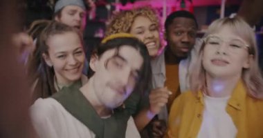 Genç adam vlogger arkadaşlarıyla dans ediyor ve gece evde kameraya bakarak poz veriyor. Modern yaşam tarzı ve vlog konsepti.