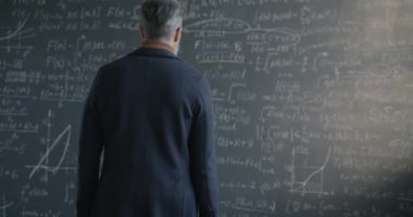 Karatahtaya yürüyen ve matematik formülünün altını çizen bilim gelişimini düşünen bir adam. Eğitim ve matematik kavramı.