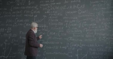 Üniversite oditoryumunda yürüyen zeki kıdemli adam karatahtadaki formülü düşünerek bilime odaklanmış. Profesör ve bilgi konsepti.