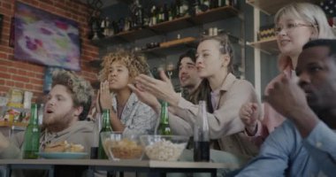 TV 'de spor müsabakaları izleyen, evdeki maçın keyfini çıkaran çeşitli öğrenci gruplarının yavaş çekimleri. Gençlik ve eğlence etkinliği konsepti.