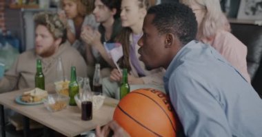 Bir grup genç sporcu televizyonda basketbol maçı izleyip Amerika 'nın bayrağını ve topunu tutuyorlar. Arkadaşlık ve eğlence konsepti.