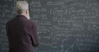 Karatahta düşünme formülüne bakan deneyimli bilim adamının yavaş hareket etmesi matematik teorisinde işe yarıyor. Eğitim ve bilim konsepti.