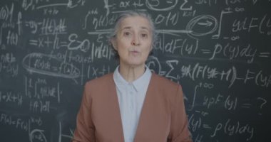 Sanal ders sırasında yazı tahtasında konuşan ve formülü gösteren son sınıf kadın cebir öğretmeninin portresi. Uzaklık eğitimi ve insanların kavramı.