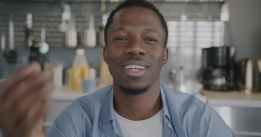 Evdeki mutfaktan çevrimiçi video görüşmeleri sırasında konuşan ve el kol hareketi yapan neşeli Afrikalı Amerikalı adamın portresi. Sanal toplantı ve iletişim konsepti.