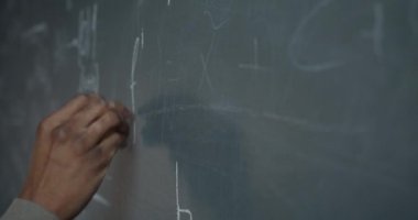 Erkek el yazısı formülünü tebeşirle karatahtaya yakın çekim yaparken bilim adamı da hesaplama ve araştırma yapıyor. Bilim ve matematik kavramı.
