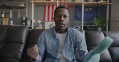 Arka planda AB ve ABD ulusal bayraklarıyla oynanan maçın keyfini sürerken, Afrikalı Amerikalı mutlu erkek sporcu taraftar maç izlerken yavaş hareket ediyor