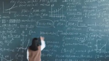 Akademik araştırmalarda çalışan genç bayan bilim adamının laboratuvarda tahtaya yazı yazması zaman aşımı. Üniversite eğitimi ve mesleki meslek kavramı.