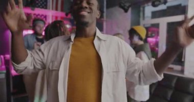 Tasasız Afrikalı Amerikalı öğrenci portresi. Gece partisinde arkadaşlarıyla dans ediyor. Aydınlanmış evde. Gençlik ve eğlence konsepti.