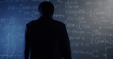 Afrika kökenli Amerikalı bir kadının karatahta duvarına doğru yürümesi ve fizik formülünün altını çizerek çözümü düşünmesi. Araştırma ve eğitim kavramı.