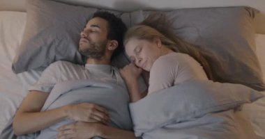 Genç ve güzel bir çift yatakta yatar ve sabahın erken saatlerinde karanlık yatak odasında sarılırlar. İlişki ve rahatlama kavramı.
