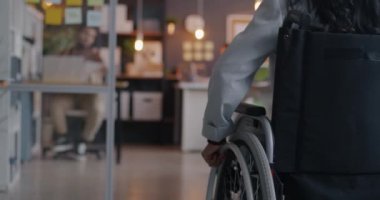 Tekerlekli sandalyedeki engelli iş kadınının yavaş çekimde iş yerine yaklaşması. Engelli iş adamı ve kapsayıcı çalışma alanı kavramı.