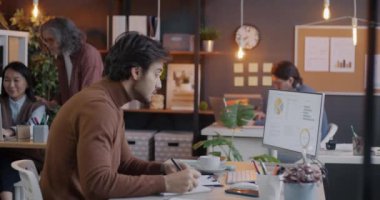 Bilgisayarla çalışan Orta Doğulu bir adam sonra da ofiste kıdemli beyaz kadın meslektaşla konuşuyor. Profesyonel işbirliği ve işyeri konsepti.