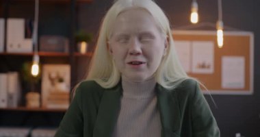 Güzel albino kadın ofis çalışanının portresi çevrimiçi video görüşmesi yapıyor ve akşamları dahil iş yerindeki kameraya bakıyor. İş ve iletişim konsepti.