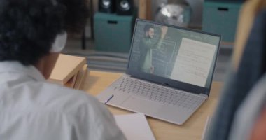Bilgisayarla online ders izleyen Afro-Amerikalı öğrenci öğretmenlerin uzaktan eğitim ile ilgili notlar yazmalarını dinliyor. E-öğrenme ve modern teknoloji kavramı.